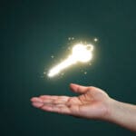 Hand holding magical hovering key symbolizing start of author journey